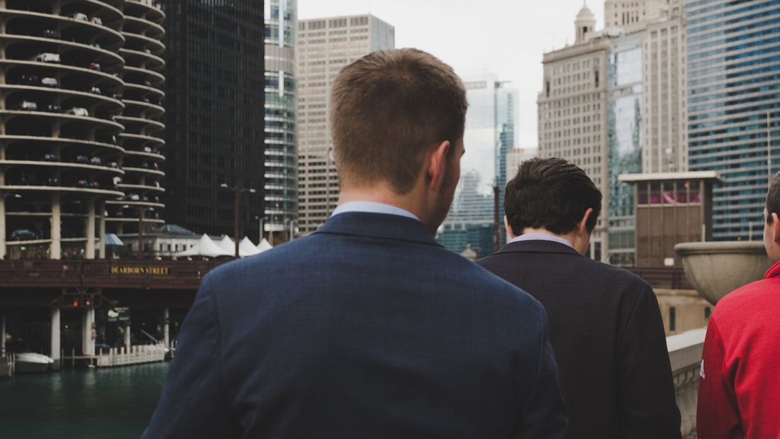 man wearing blue blazer standing behind two men during daaytime