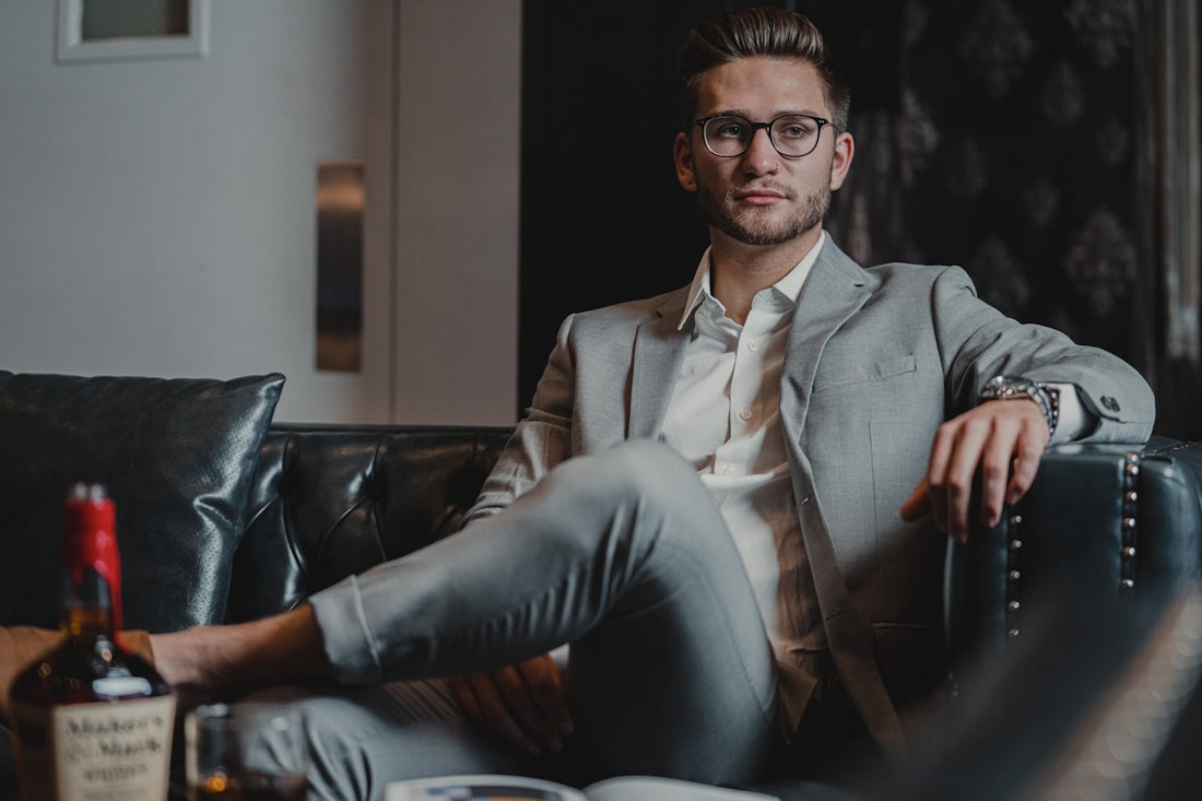 man in gray suit sitting on black leather couch