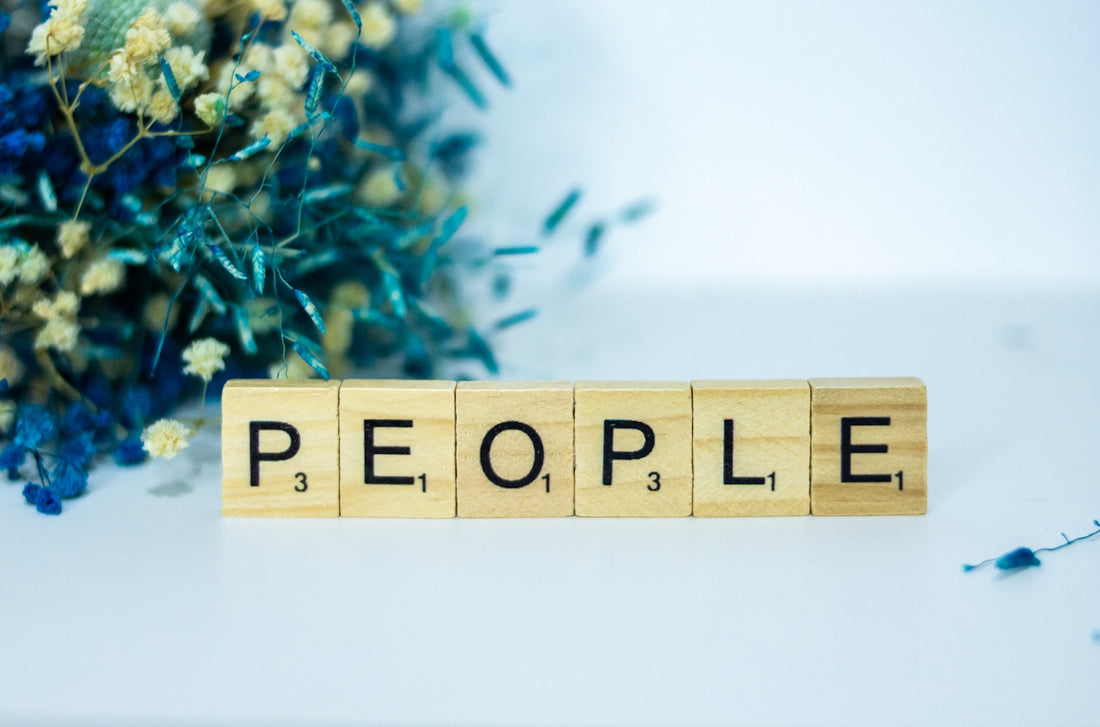 a wooden block spelling people next to a bouquet of flowers