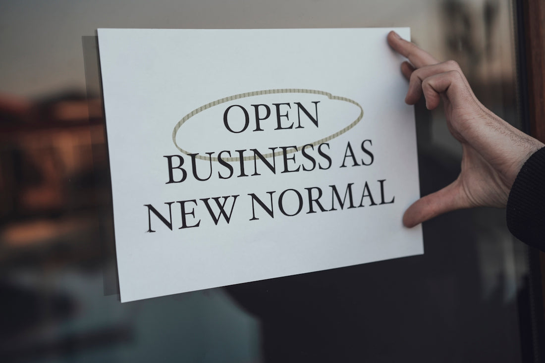 a person holding a sign that says open business as new normal