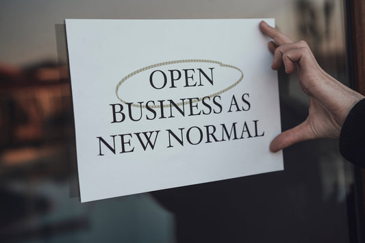 a person holding a sign that says open business as new normal