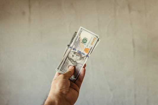 a person holding a stack of money in their hand
