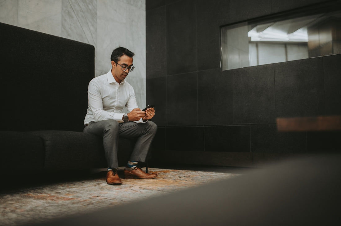 a man sitting on a couch looking at his cell phone