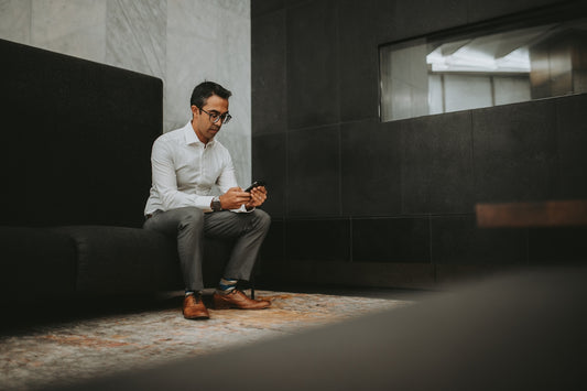 a man sitting on a couch looking at his cell phone