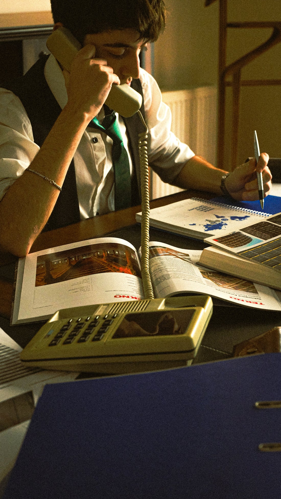 A person sitting at a desk with a book and a phone