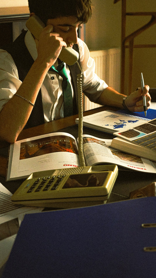 A person sitting at a desk with a book and a phone