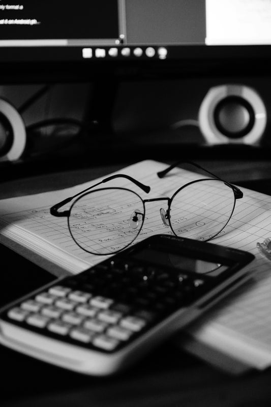 A computer desk with a keyboard, mouse and glasses on it