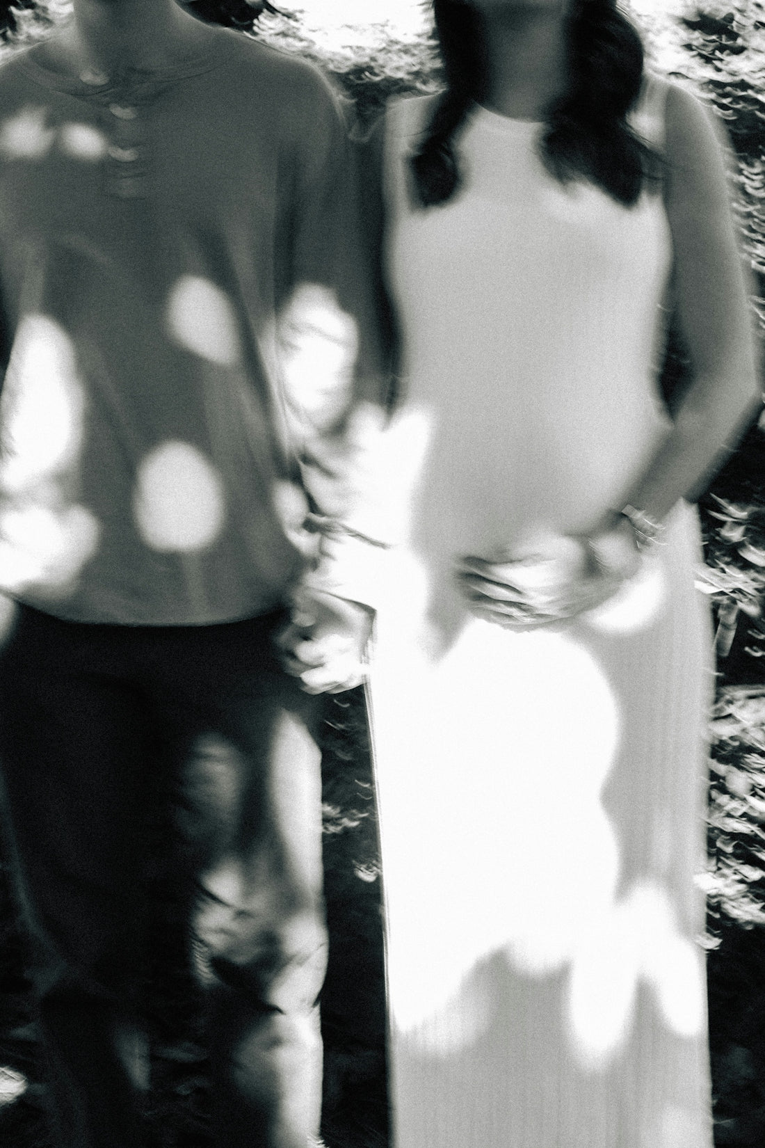 Pregnant woman and partner holding hands outside.