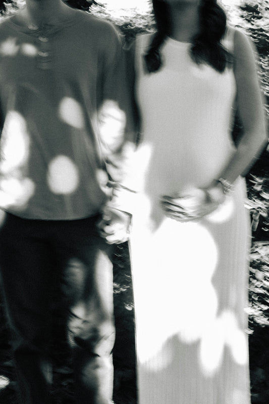 Pregnant woman and partner holding hands outside.