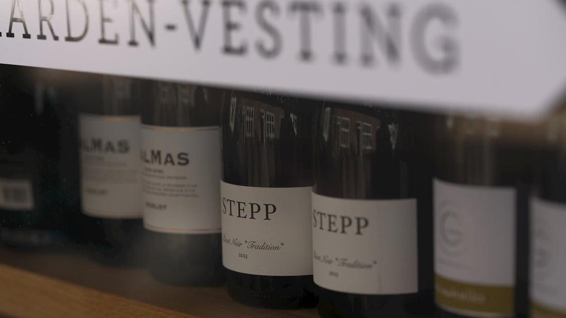 Wine bottles are lined up on a shelf.