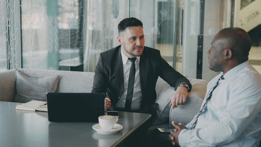 Two businessmen talking at a table with laptop.