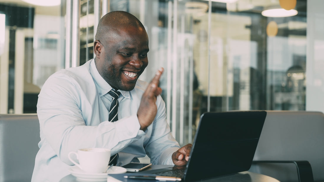 Man waving during a video call on laptop.