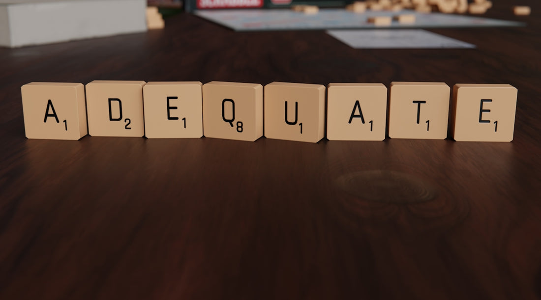 Scrabble tiles spell out the word adequate.