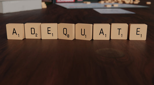 Scrabble tiles spell out the word adequate.