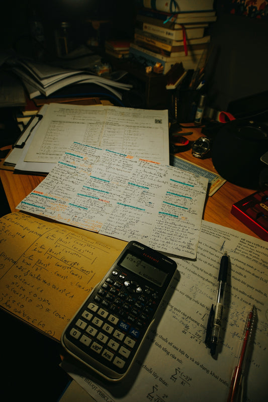Desk with calculator, pens, and study papers
